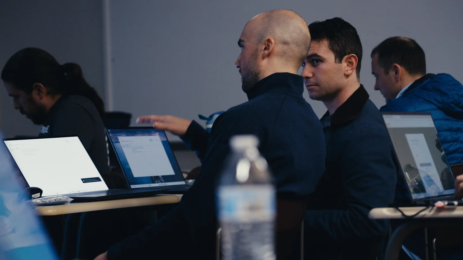 Two men looking at a screen together at a workbench