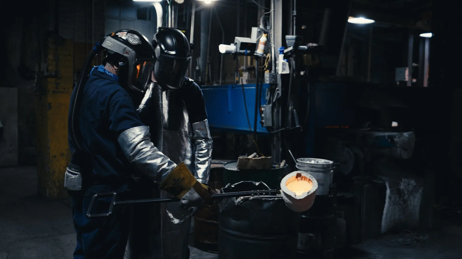 A worker in aluminised heat gear tipping molten metal into a mould
