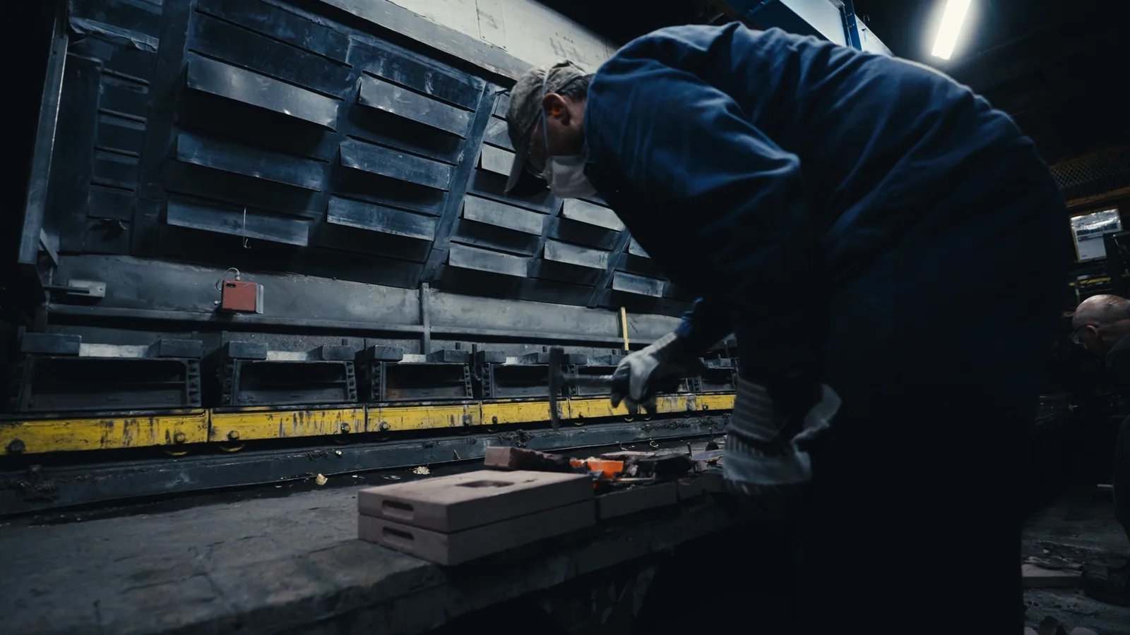 A worker leaning over a mould box on a foundry floor