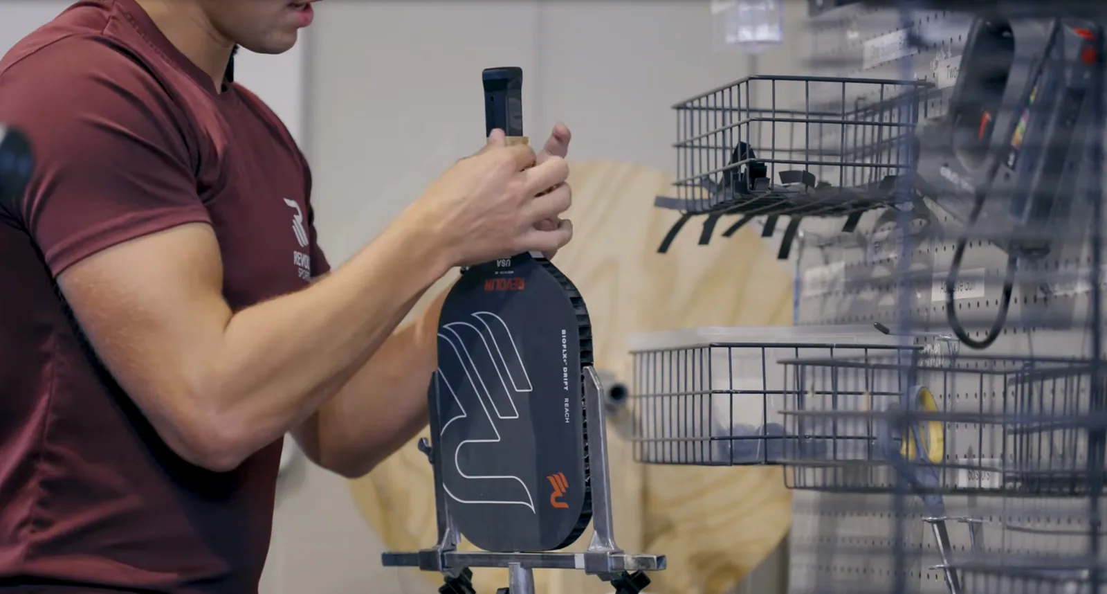 Hands holding a pickleball paddle with a dark carbon-fibre face